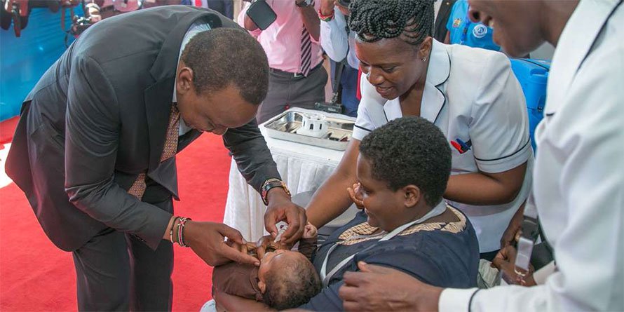 President Uhuru Kenyatta gives a polio shot to an infant during the